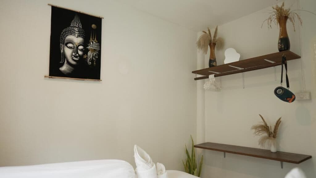Una habitación con una cama, una repisa en la pared con objetos decorativos y una obra de arte enmarcada.