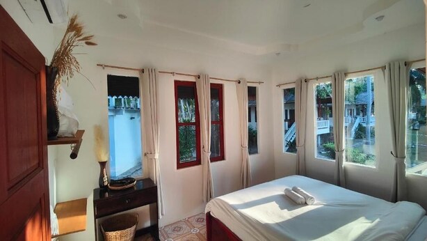 Un dormitorio con cama, escritorio, silla y ventana con cortinas.