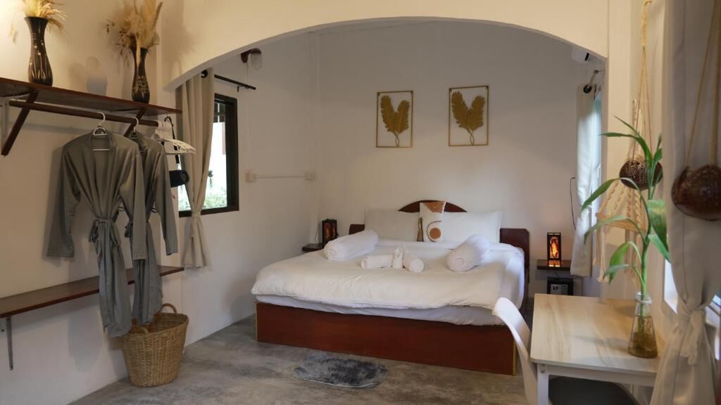 A bedroom with a bed, bedside tables, a hanging robe rack, and a window with curtains.