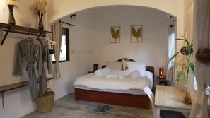 A bedroom with a bed, bedside tables, a hanging robe rack, and a window with curtains.
