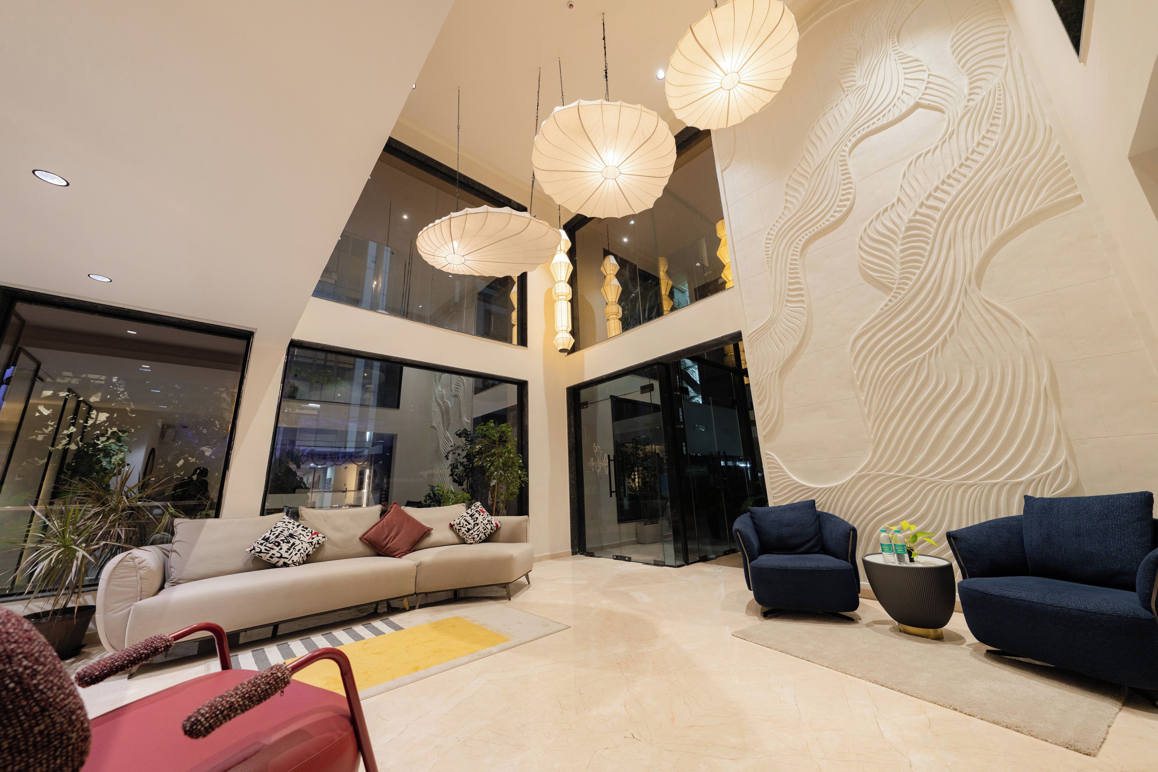 Un interior moderno con techo alto, un mural grande en la pared y un área de estar con sofás y sillones.
