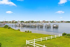 A marina with boats docked, a white fence, and houses in the background. - 🌊🏖️ Sand Dollar W-210 | Steps to Beach + Bunk Room | Pensacola Beach (Pensacola Beach)