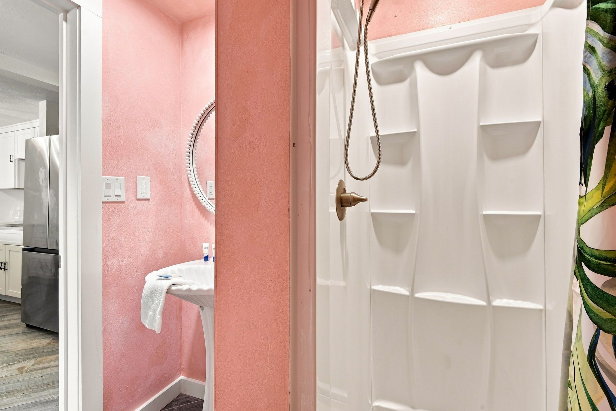 Ein Badezimmer mit weißem Waschbecken, einem Spiegel und einer Duschkabine.