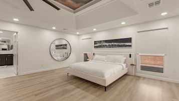 Un dormitorio con una cama grande, un espejo redondo y obras de arte en las paredes.