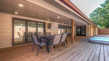 Eine Außenpatio mit einer Holzdachterrasse, einem Tisch mit Stühlen und einem fest eingebauten Bildschirm.