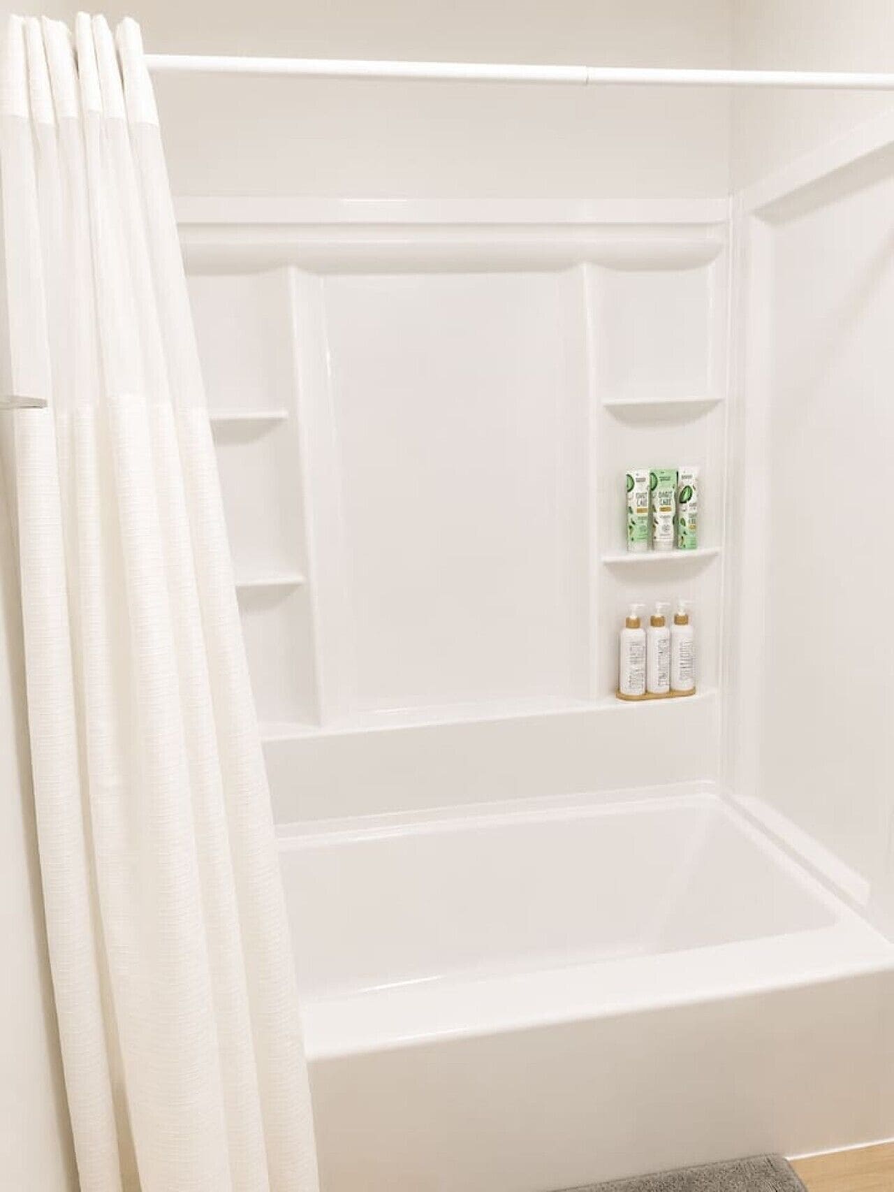 Une baignoire blanche avec un rideau de douche, une étagère avec des articles de toilette et un porte-serviettes.
