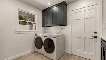 A laundry room with a double washer and dryer, a window with a view, and a door.