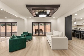 Ein modernes Wohnzimmer mit einem weißen Sofa, einem grünen Sofa und einem Essbereich mit Tisch und Stühlen.