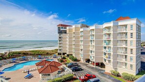 Un hotel su più piani con piscina, vista sulla spiaggia e area parcheggio.