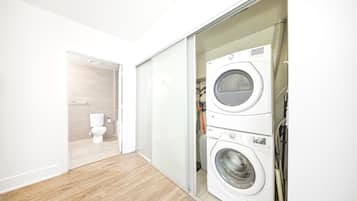 A laundry room with a washing machine and dryer, a toilet, and a sliding door closet.