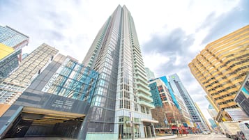 A modern high-rise building with a glass facade, service entrance, and a coffee shop on the ground floor.
