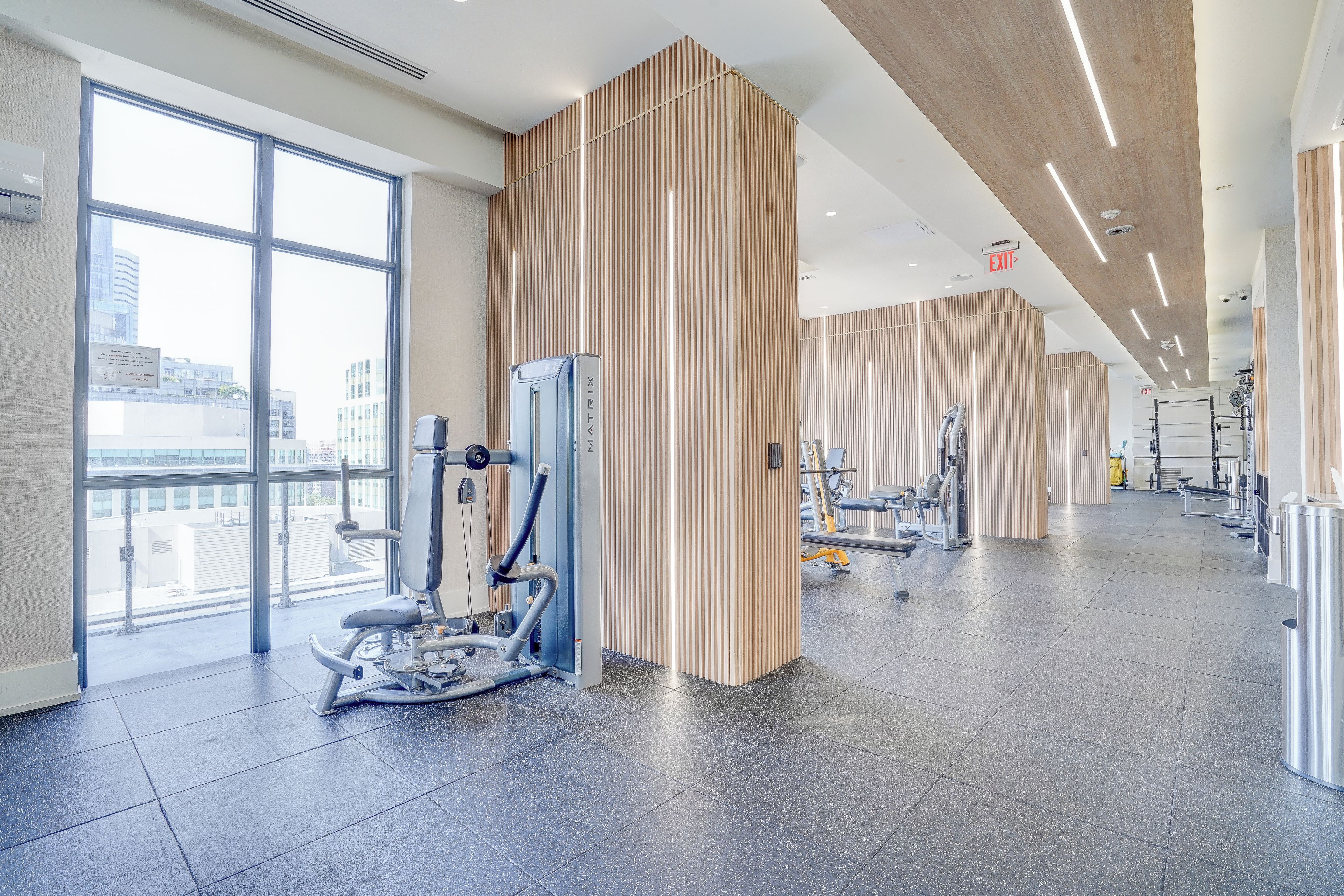 A modern gym with exercise equipment, large windows, and a clean, spacious interior.