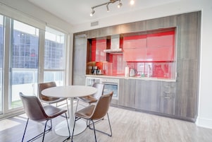 Une cuisine moderne avec une table de salle à manger ronde et quatre chaises, de grandes fenêtres et une vue sur l’extérieur.
