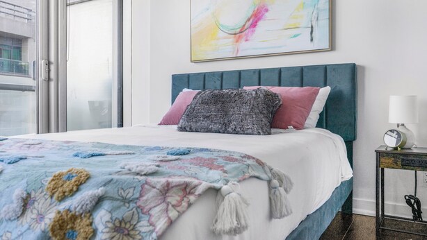 A bedroom with a bed, a nightstand, a lamp, and a window.