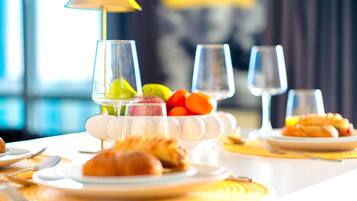 A dining table with plates of food, glasses of water, and a fruit bowl.