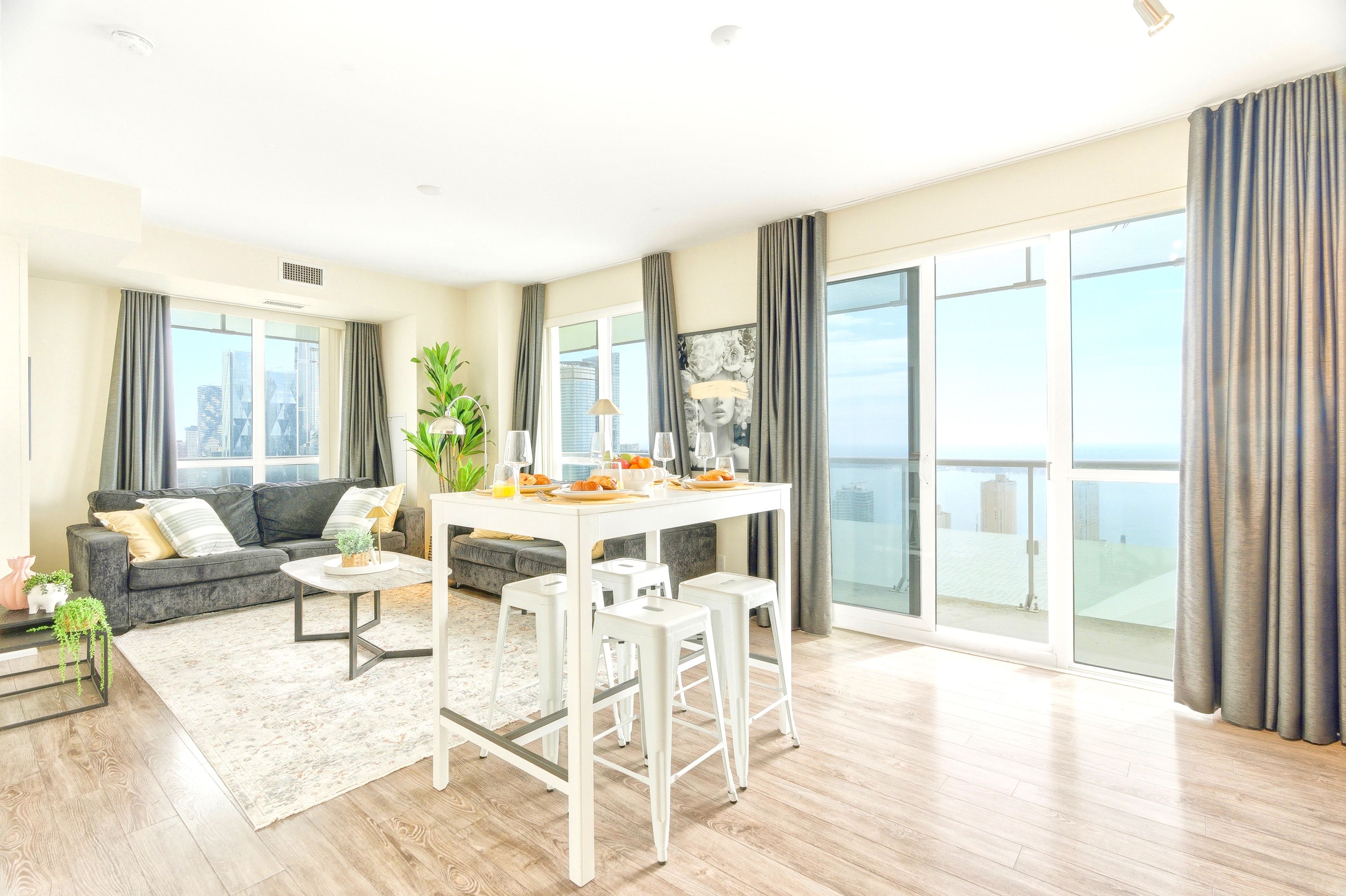 A modern living room with a sofa, a dining table, and a balcony with a view.