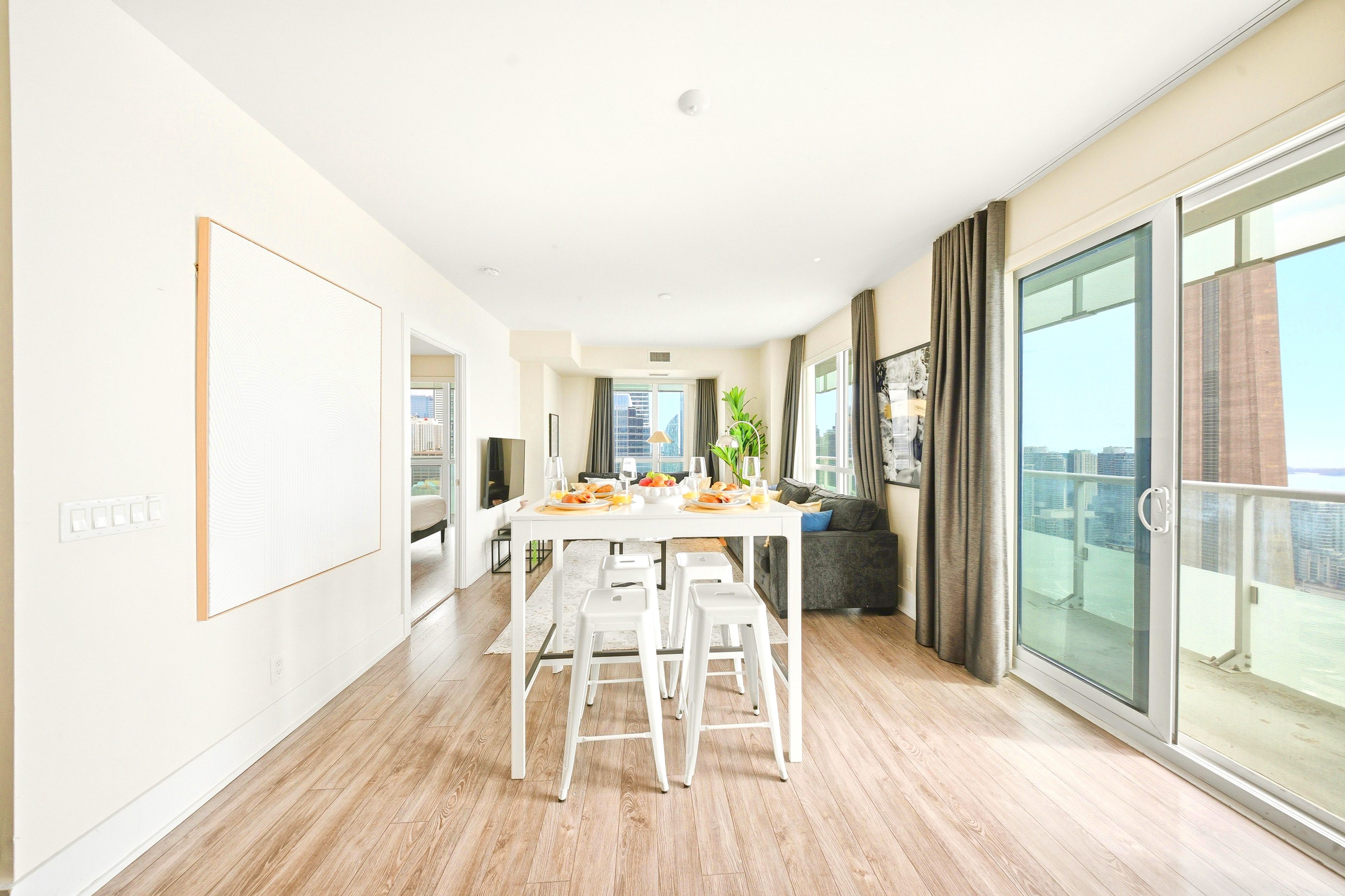 A modern apartment with a dining area, a balcony with a view, and a kitchen.