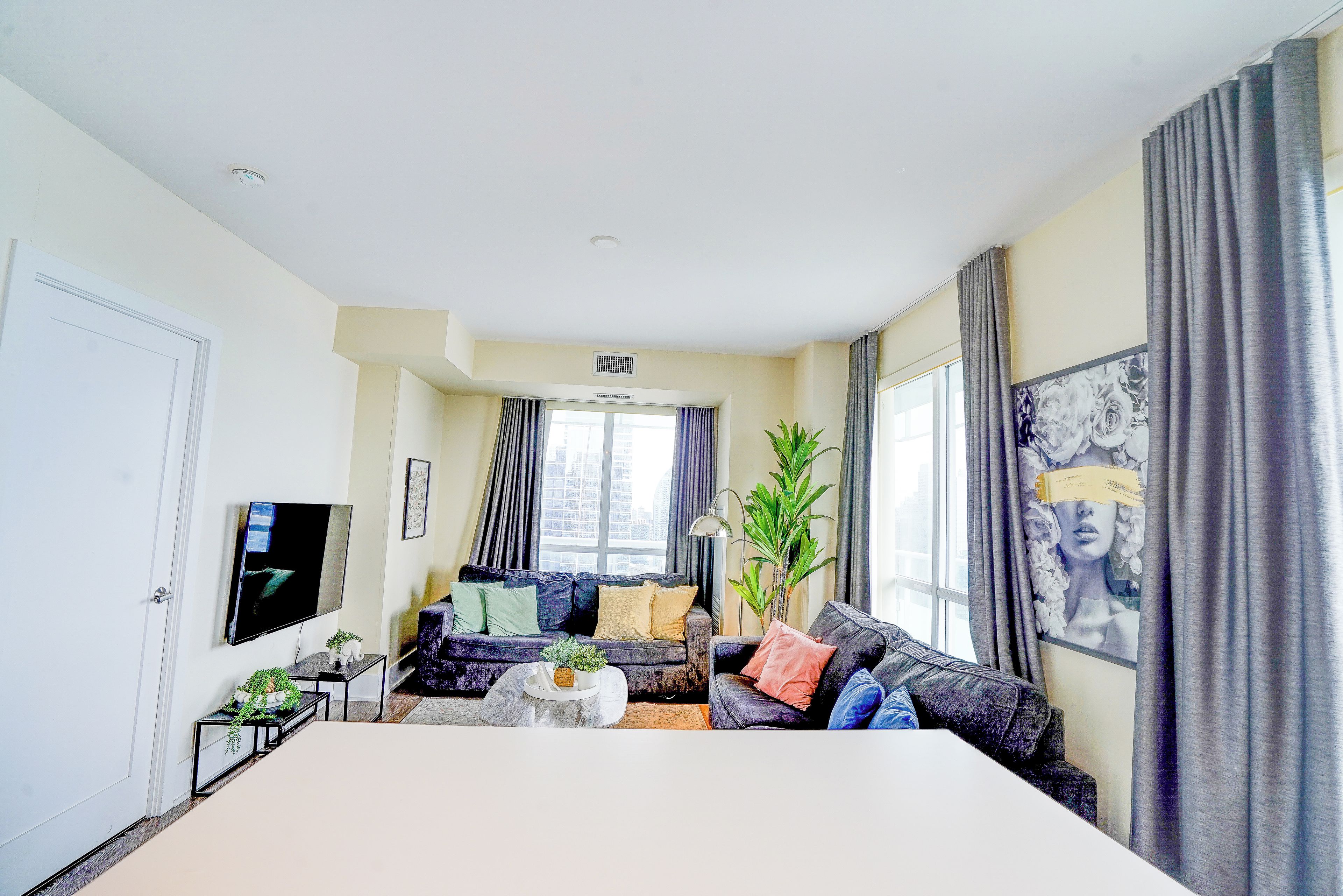 A modern living room with a sofa set, a coffee table, a TV, and a large window with curtains.