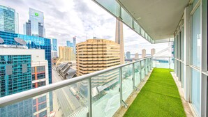 Ein Balkon mit Glasgeländer und Blick auf eine Skyline mit modernen Gebäuden.