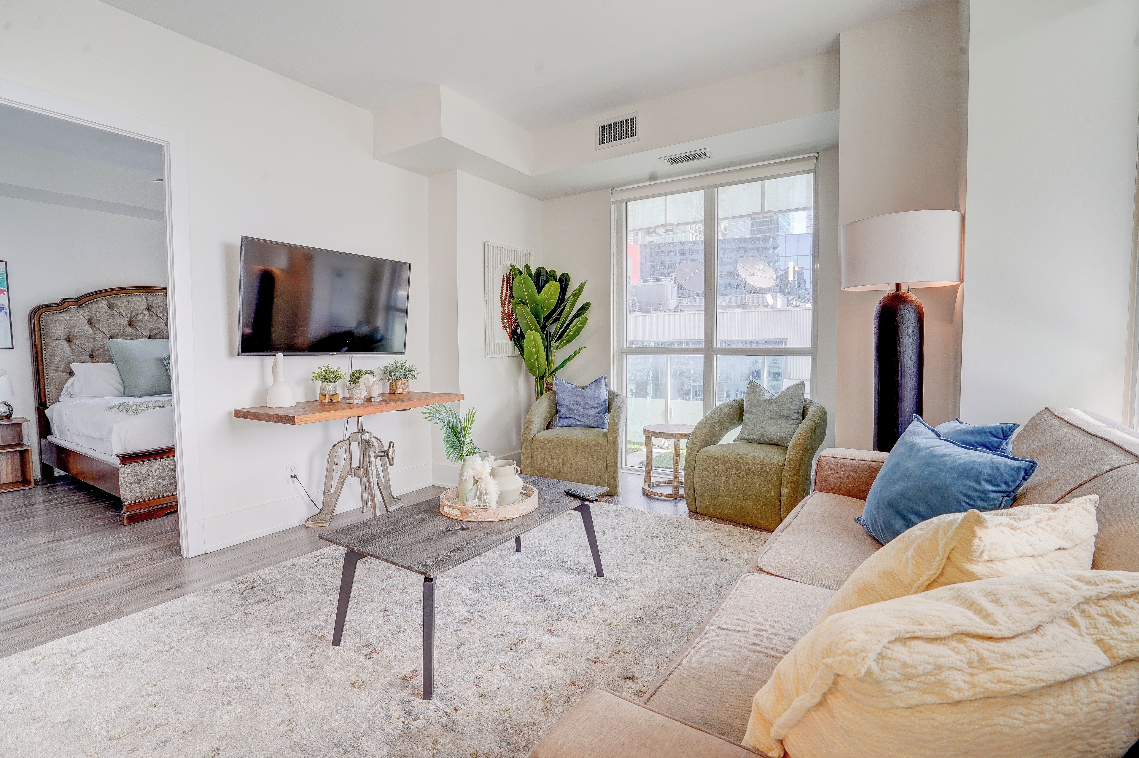 A modern living room with a television, seating area, and large windows.