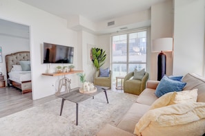 Una sala de estar moderna con televisión, zona de estar y ventanas amplias.