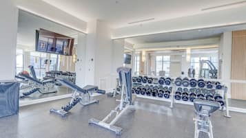 Une salle de sport équipée de divers appareils d’exercice, notamment des tapis de course et des haltères.