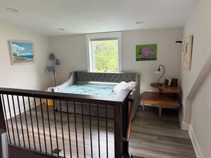 Ein Schlafzimmer mit Bett, Fenster, Gemälde und Schreibtisch.