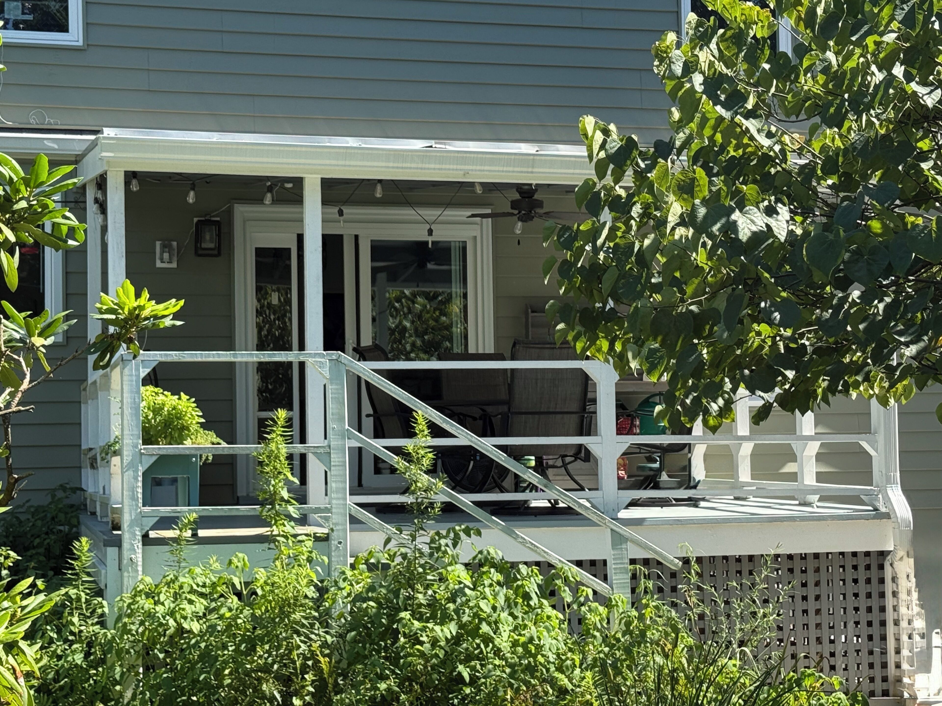 A house with a covered porch, outdoor furniture, and a small garden area.