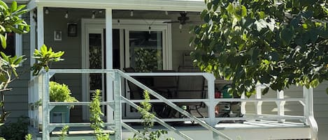 A house with a covered porch, outdoor furniture, and a small garden area.