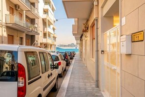 A narrow street with parked cars and a building with a sign indicating it is a hotel. - ALL Spa and Relax | Mediterranean Retreat (Monopoli)