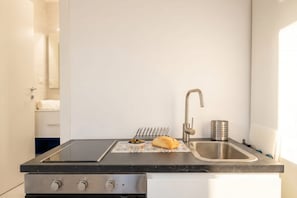 A kitchen with a black countertop, a stainless steel sink, a built-in oven, and a small bowl of olives and bread. - ALL Spa and Relax | Mediterranean Retreat (Monopoli)