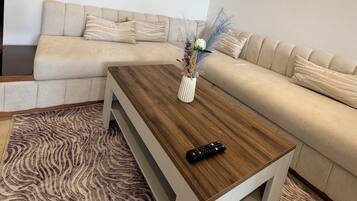 A modern living room with a beige sectional sofa, a wooden coffee table, and a zebra-patterned rug.