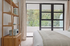 A bedroom with a bed, a wooden bookshelf, and a large window with a view of greenery. - One bedroom apartment near beach and Westbourne (Bournemouth)