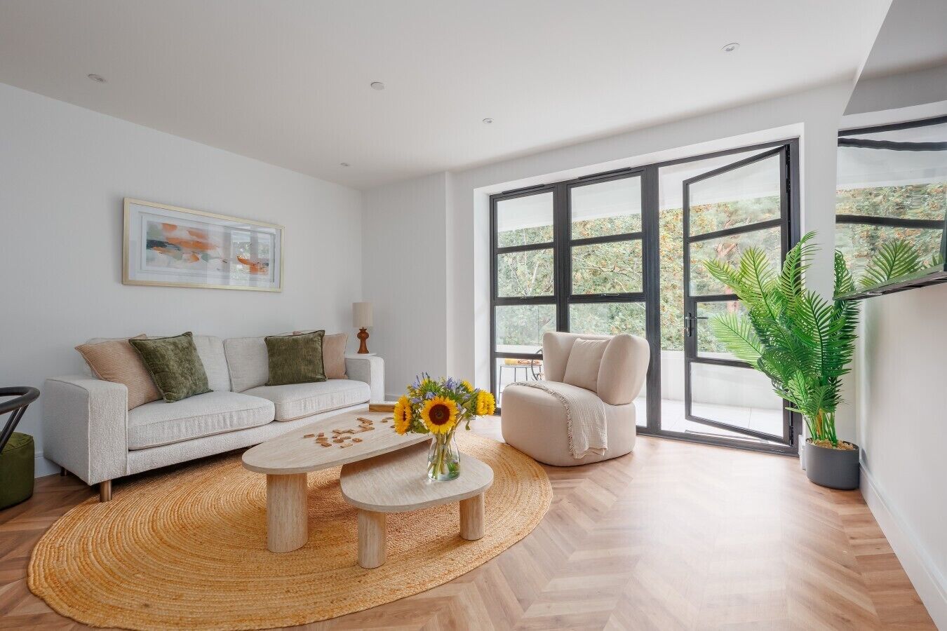 Un salon moderne avec un canapé, un fauteuil, une table basse et une grande fenêtre donnant sur un beau paysage.