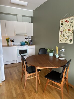 A dining area with a wooden table and chairs, a kitchen in the background, and a botanical illustration on the wall. - Apartment in the middle of Tromsø City (Tromsø)