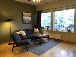 A modern living room with a sofa, armchair, and coffee table, a floor lamp, and a painting on the wall. - Apartment in the middle of Tromsø City (Tromsø)