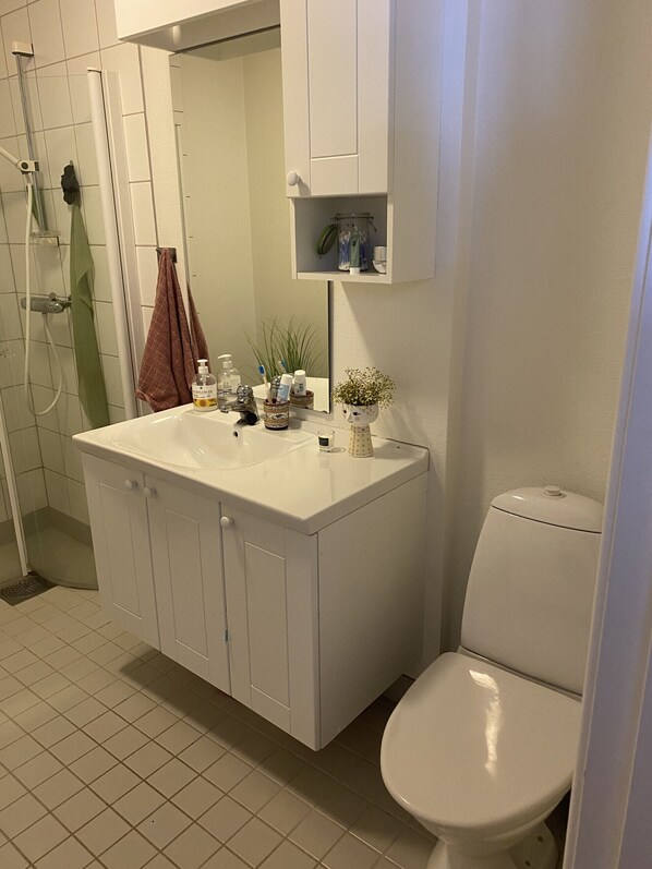 A bathroom with a white sink, a toilet, and a shower. - Apartment in the middle of Tromsø City (Tromsø)