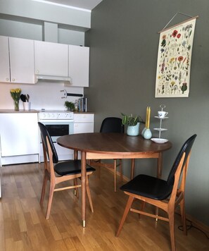 A modern kitchen with white cabinets, a wooden dining table with four chairs, and a wall-mounted botanical print. - Apartment in the middle of Tromsø City (Tromsø)