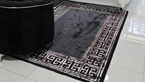 Habitación de hotel con una cama, una silla negra, una alfombra y una ventana con vistas.