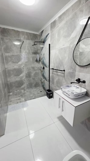A modern bathroom with a shower, a toilet, and a sink.