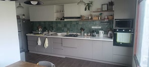 Una cocina moderna con gabinetes grises, una encimera blanca y un microondas integrado.