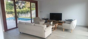 Una sala de estar con sofá, mesa de centro, televisor y sillas.