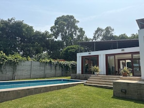 Una casa moderna con piscina, un muro de piedra y un jardín.