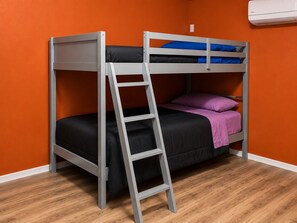 Un lit superposé avec une échelle, une literie noire et bleue, et un oreiller violet.