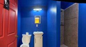 Een badkamer met een rode deur, een wit toilet, een wastafel en een douchehoek.