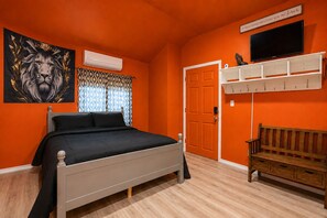 A bedroom with a bed, a bench, a television, and a door. - Lakefront Escape on Twin Lake Cabin + Trailer (Twin Lake)