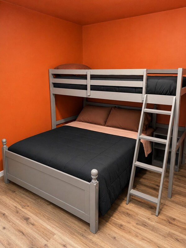 A bunk bed with a ladder, a black mattress, and a wooden floor.