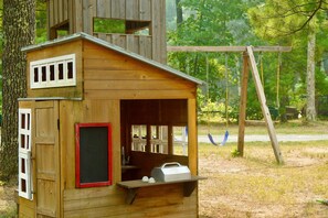 A wooden cabin with a porch and a swing set in a wooded area. - Lakefront Sacred Escape on Twin Lake - Cabin (Twin Lake)