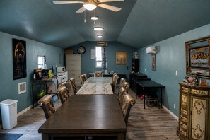 A dining area with a long table and chairs, a ceiling fan, and a microwave on the wall. - Lakefront Sacred Escape on Twin Lake - Cabin (Twin Lake)