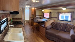 Ein kompaktes Wohnmobil-Interieur mit Küchenzeile, Essbereich und Sitzgelegenheit.